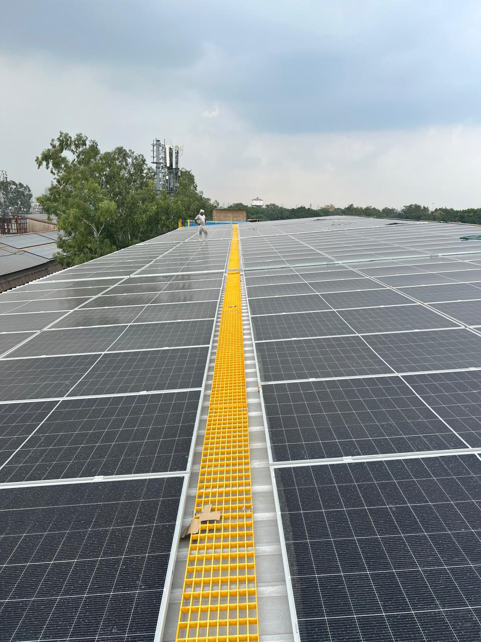 Yellow access walkway between rows of rooftop solar panels at the 300 kW installation